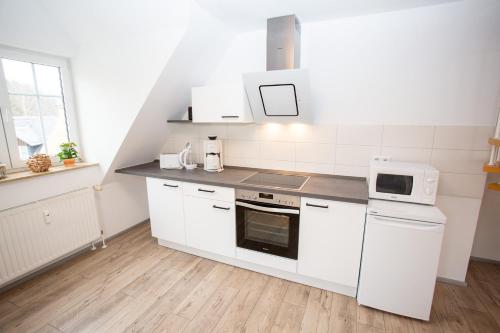a kitchen with white cabinets and a stove top oven at Ferienwohnung Zschopau Zentrum in Zschopau