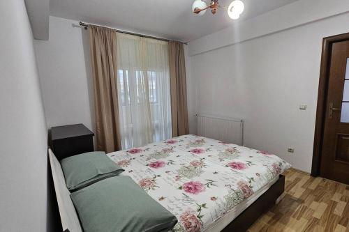1 Schlafzimmer mit einem Bett mit einer Blumendecke und einem Fenster in der Unterkunft Radauti Residence 1P in Rădăuţi