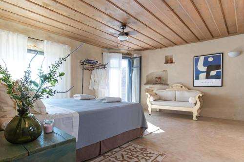 Un dormitorio con una cama y un sofá en una habitación. en Lethos Villa - Tinos, en Kionia