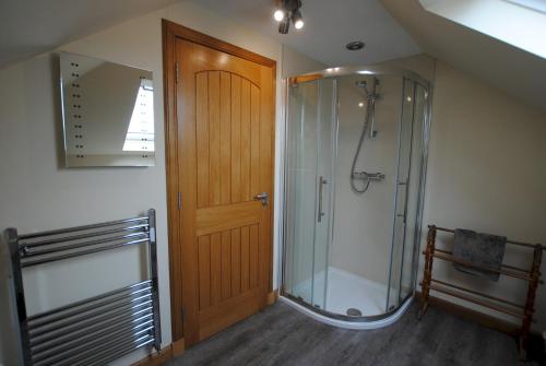 a bathroom with a shower and a wooden door at Stronvar- coastal home with sea views in Pittenweem