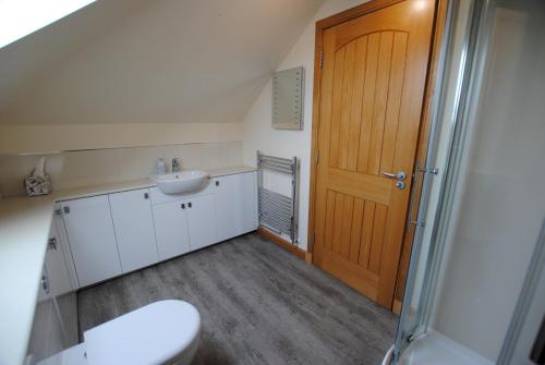 a bathroom with a toilet and a sink and a wooden door at Stronvar- coastal home with sea views in Pittenweem