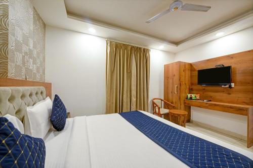 a hotel room with a bed and a flat screen tv at Hotel Gloory Suites Near Delhi Airport in New Delhi