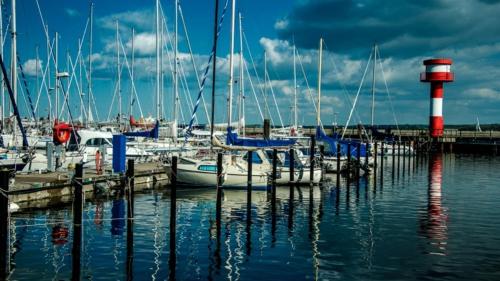 a group of boats docked in a marina with a lighthouse at Amselpark in Barkelsby