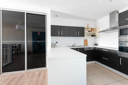 une cuisine avec des armoires noires et un comptoir blanc dans l'établissement Family cocoon in Carcassonne, à Carcassonne