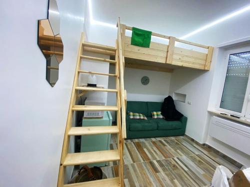 a bunk bed in a room with a green couch at Nido sul mare! in Torvaianica