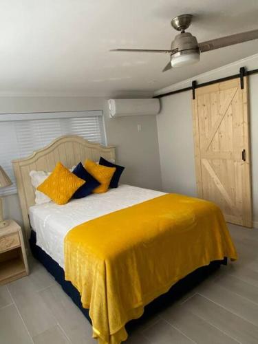 een slaapkamer met een bed met een gele deken erop bij Chez Rose Bungalow in Nassau
