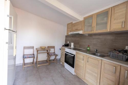 a kitchen with wooden cabinets and a sink and a table at EVRIAKI'S HOUSE in Apidias Lakos