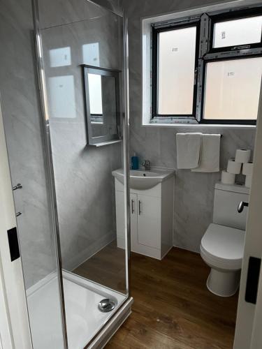 a bathroom with a shower and a toilet and a sink at The Barrington Hotel in New Barnet