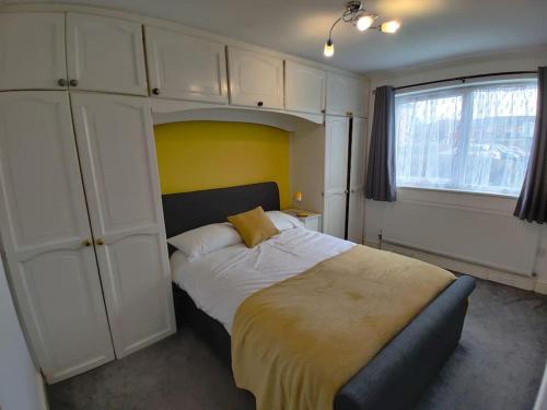 a bedroom with a large bed with a yellow wall at Cosy and modern two bedroom flat near Heathrow in Hayes