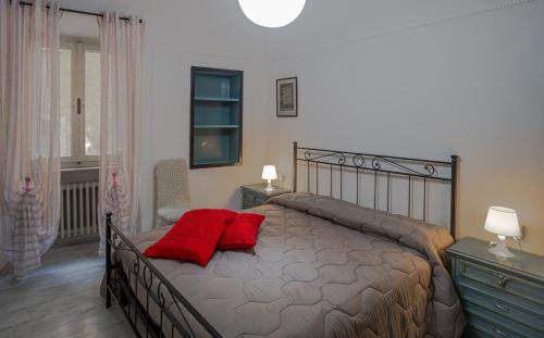 a bedroom with a bed with two red pillows on it at All'ombra del Campanile in Volterra