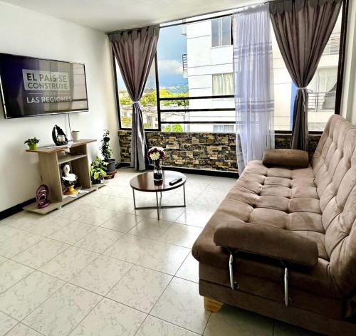 a living room with a couch and a large window at Cómodo apartamento en la Villa Olímpica de Pereira in Pereira