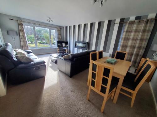 a living room with a couch and a table at Aviemore Bungalow, Dalfaber in Aviemore