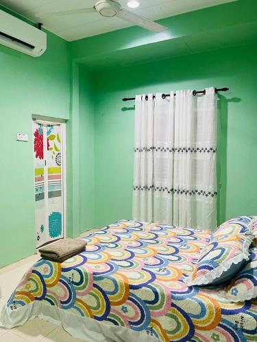 een slaapkamer met een bed en een groene muur bij Mak kuntum homestay in Sungai Petani