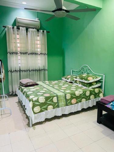 een groene slaapkamer met een bed en een plafondventilator bij Mak kuntum homestay in Sungai Petani