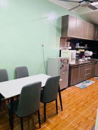 een keuken met een tafel en stoelen en een koelkast bij Mak kuntum homestay in Sungai Petani