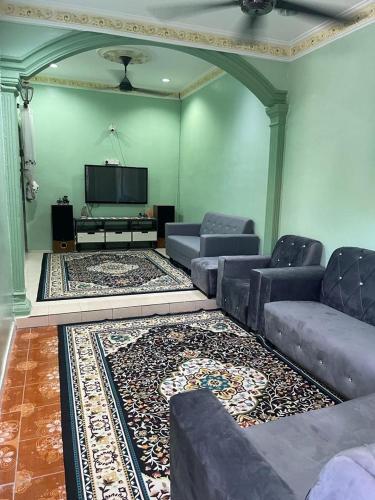 een woonkamer met banken en een flatscreen-tv bij Mak kuntum homestay in Sungai Petani