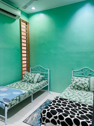 twee bedden in een kamer met een groene muur bij Mak kuntum homestay in Sungai Petani