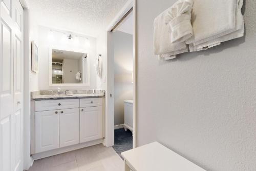 een witte badkamer met een wastafel en een spiegel bij Island Princess 411 in Fort Walton Beach