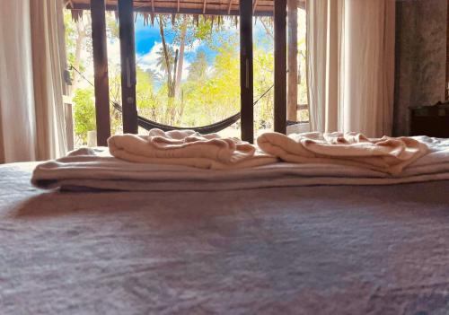a pile of towels sitting on a bed in front of a window at Villa Wonderworld Resort in Ban Nua