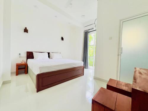 ein weißes Schlafzimmer mit einem Bett und einem Fenster in der Unterkunft Lavish Weligama in Weligama