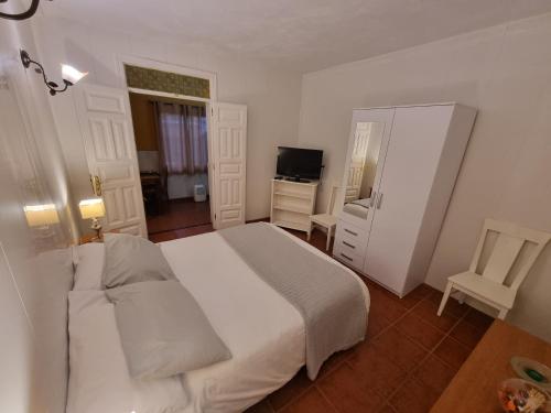 1 dormitorio con 1 cama blanca y TV en Vivienda Vacacional Ca Na Paula en La Orotava