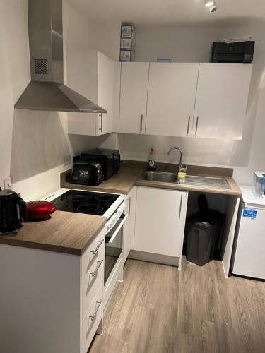 a kitchen with white cabinets and a stove top oven at Perfect flat next to Wembley Stadium in London