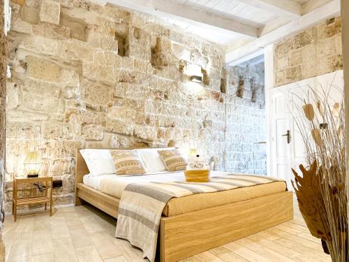 una camera da letto con un muro in pietra e un letto di Old tuff apartments a Polignano a Mare