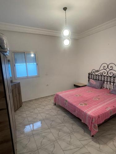 a bedroom with a bed with a pink bedspread at DIaR MAHER in Al Maqārisah