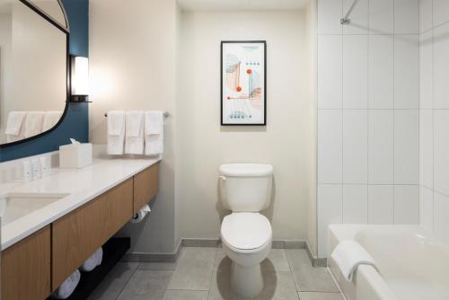 a bathroom with a toilet and a sink and a tub at Hotel Landy Orlando Universal Blvd, a Tribute Portfolio Hotel in Orlando