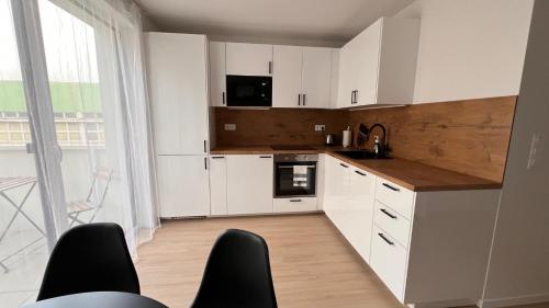 a kitchen with white cabinets and a large window at 2 room Apartment with terrace, new building, B1 in Bratislava