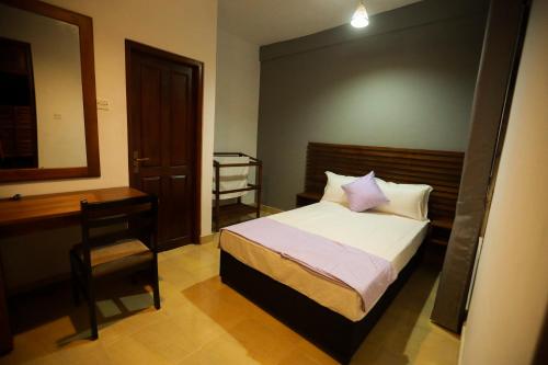 a bedroom with a bed and a desk and a chair at Stellar Inn in Peradeniya