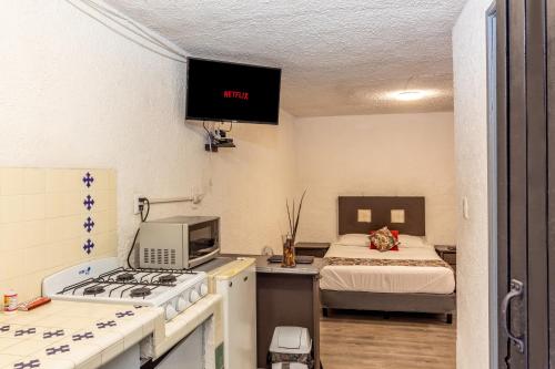 a small room with a bed and a kitchen with a stove at Loft Privado con Cocina, Vive Chapalita 3 in Guadalajara