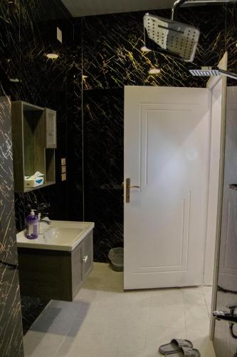 a bathroom with a white door and a sink at شقق نرمادا المفروشة فرع قباء in Medina