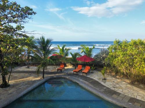 a swimming pool with chairs and umbrellas and the ocean at Casa Playa San Diego in San Diego