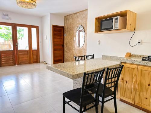 a kitchen with a counter with chairs and a microwave at Pousada Amazing Jeri in Jericoacoara