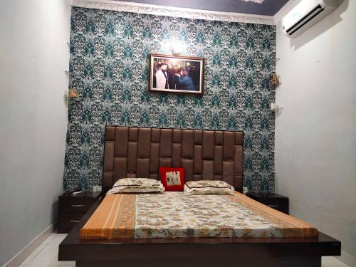 1 dormitorio con 1 cama y una foto en la pared en OYO Home Abhishek Homestay, en Pathankot