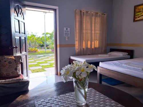 um quarto com duas camas e um vaso com flores sobre uma mesa em La Plumerias em Moalboal