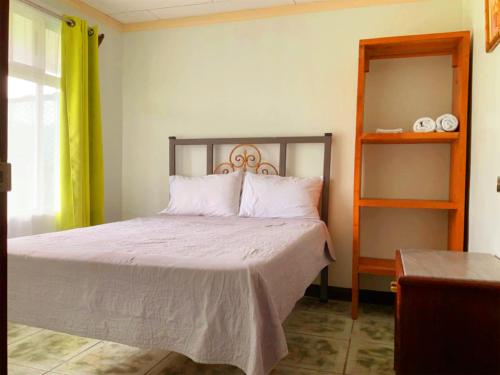 Tropical Housing by El Rodeo - Calle El Manglar في بويرتو خيمينيز: غرفة نوم بسرير ومخدات بيضاء