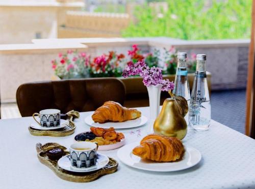 una mesa con platos de repostería y botellas de vino en Royal Historical Boutique Hotel en Baku