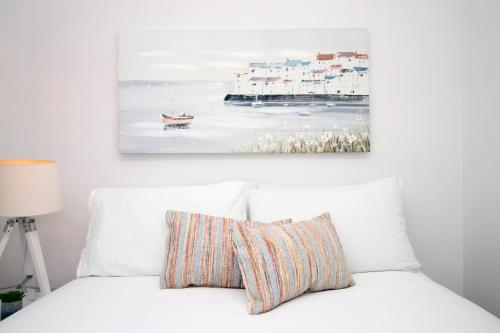 a bedroom with a white bed with a painting on the wall at Seaside town apartment 10 mins from Cardiff! in Cardiff