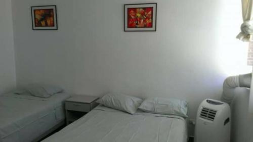 two beds in a room with two pictures on the wall at LA COLINA Casa-Hospedaje in Máncora