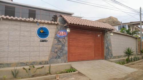 a building with a wooden door and a sign on it at LA COLINA Casa-Hospedaje in Máncora