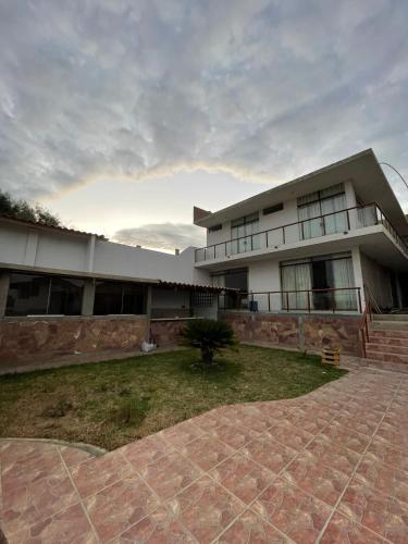 a large building with a brick yard in front of it at LA COLINA Casa-Hospedaje in Máncora