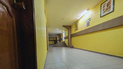 a hallway of a hospital with yellow walls and stairs at Hotel Plaza San Juan in Mexico City