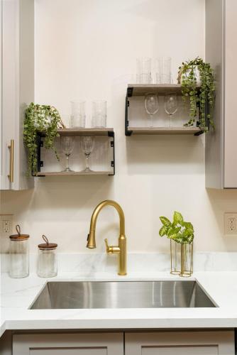 a kitchen sink with glasses and plants on the wall at The Alexandre in New Orleans
