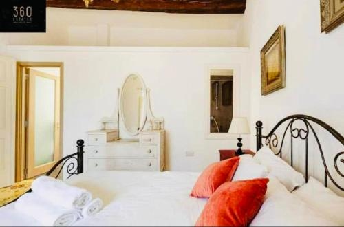 - une chambre avec un lit doté d'oreillers rouges et d'un miroir dans l'établissement Sannat Hills Farmhouse, à Sannat