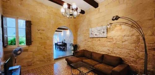 a living room with a couch and a stone wall at Sannat Hills Farmhouse in Sannat