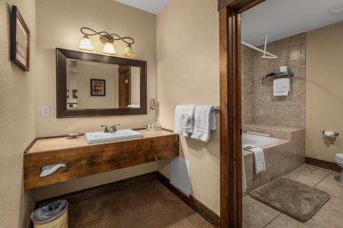 een badkamer met een wastafel, een bad en een spiegel bij Duck Inn Lodge in Whitefish