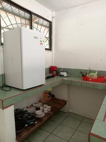 eine Küche mit einem weißen Kühlschrank und einigen Töpfen und Pfannen in der Unterkunft Dulce Horizonte in Puerto Jiménez