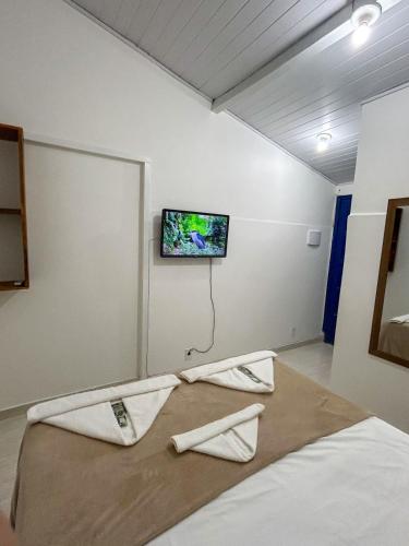 a bedroom with a bed with a tv on the wall at Hospedagem na rua da Tartaruga in Búzios